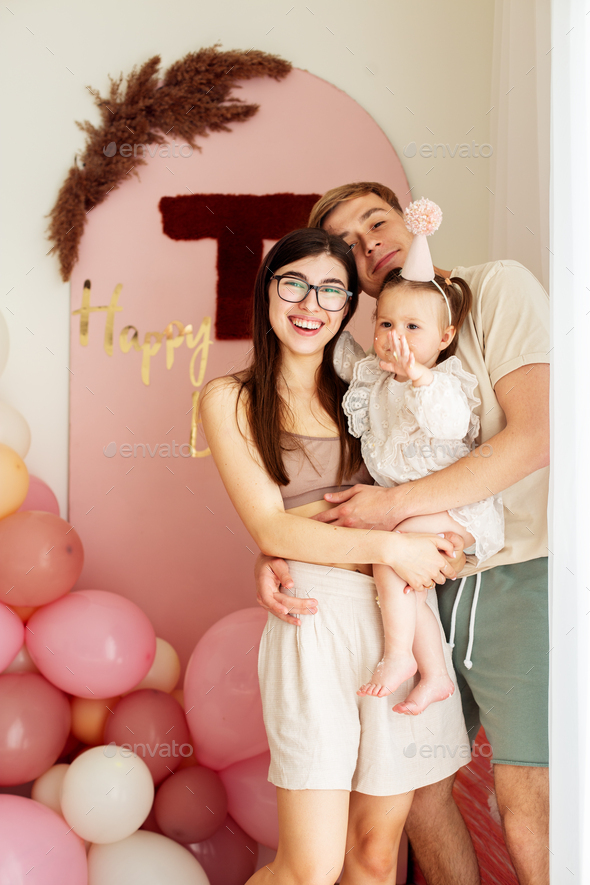 One year old little girl with daddy and mammy solemnize birthday. Happy